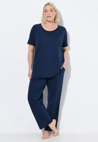 Donkerblauwe pyjama set met een losvallend shirt met korte mouwen en wijde broek, gemaakt van zachte stof met een gladde textuur.
