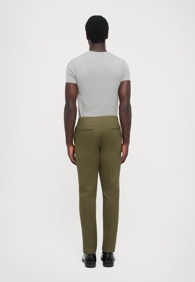 Grå kortærmet skjorte og olivengrønne skræddersyede bukser med slim fit. Bukserne har baglommer og en glat finish. Sorte sko medfølger.