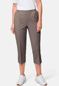 Grau geschnittene Hosen mit elastischem Bund, flacher Vorderseite, zwei Seitentaschen und glatter Textur. Getragen mit weißen Sportschuhen.