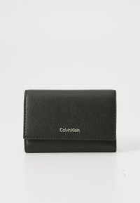 Svart teksturert skinnlommebok fra Calvin Klein med klaffestenging og gulldebossert logo sentralt på forsiden, mot en enkel bakgrunn.