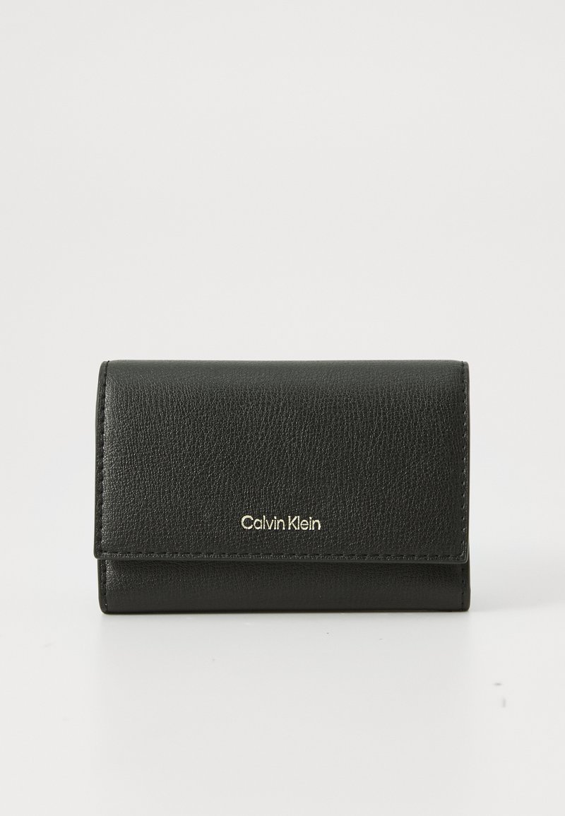 Cartera de cuero negro texturizado de Calvin Klein con cierre de solapa y logotipo dorado en relieve centrado en la parte frontal, sobre un fondo liso.