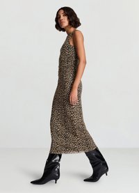 Maxikleid mit Leopardenmuster, figurbetontem Oberteil, gerafften Details und fließendem Rock, kombiniert mit kniehohen schwarzen Lackstiefeln.