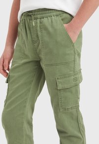 Pantaloni cargo verdi con cintura elastica, tasche laterali e grandi tasche applicate sulle cosce. Realizzati in un resistente tessuto misto cotone.