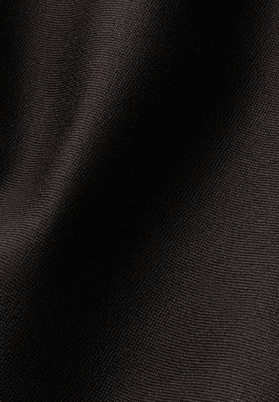 Gros plan d’un tissu noir texturé montrant un motif fin tissé avec la lumière et l’ombre créant de doux plis.