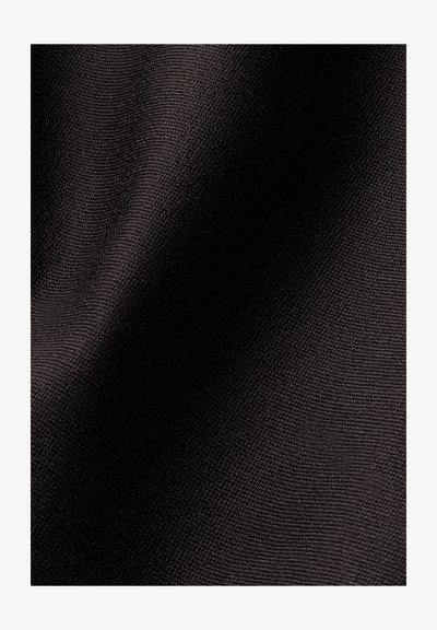 Gros plan d’un tissu noir texturé montrant un motif fin tissé avec la lumière et l’ombre créant de doux plis.