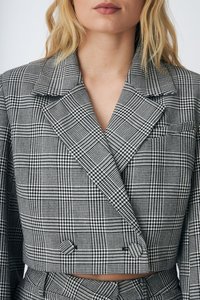 Gecarngde cropped blazer in zwart en wit, met een dubbele rij knopen, notch revers en een gestructureerde stof.