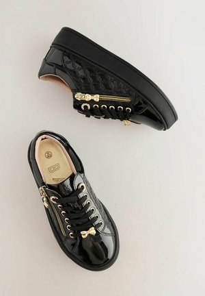 Sneaker in pelle verniciata nera con design trapuntato e dettagli in oro. Caratterizzate da lacci, zip laterale e suola in gomma nera.