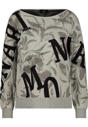 Pull gris clair à manches longues avec de grandes lettres noires et des motifs discrets de feuilles, avec des mots comme "SPIRIT" et "FREE" en texte plus petit.