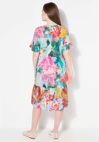 Vestido floral con colores vibrantes como rosa, verde y naranja, con un diseño en capas y mangas cortas. Tejido ligero con un corte holgado.