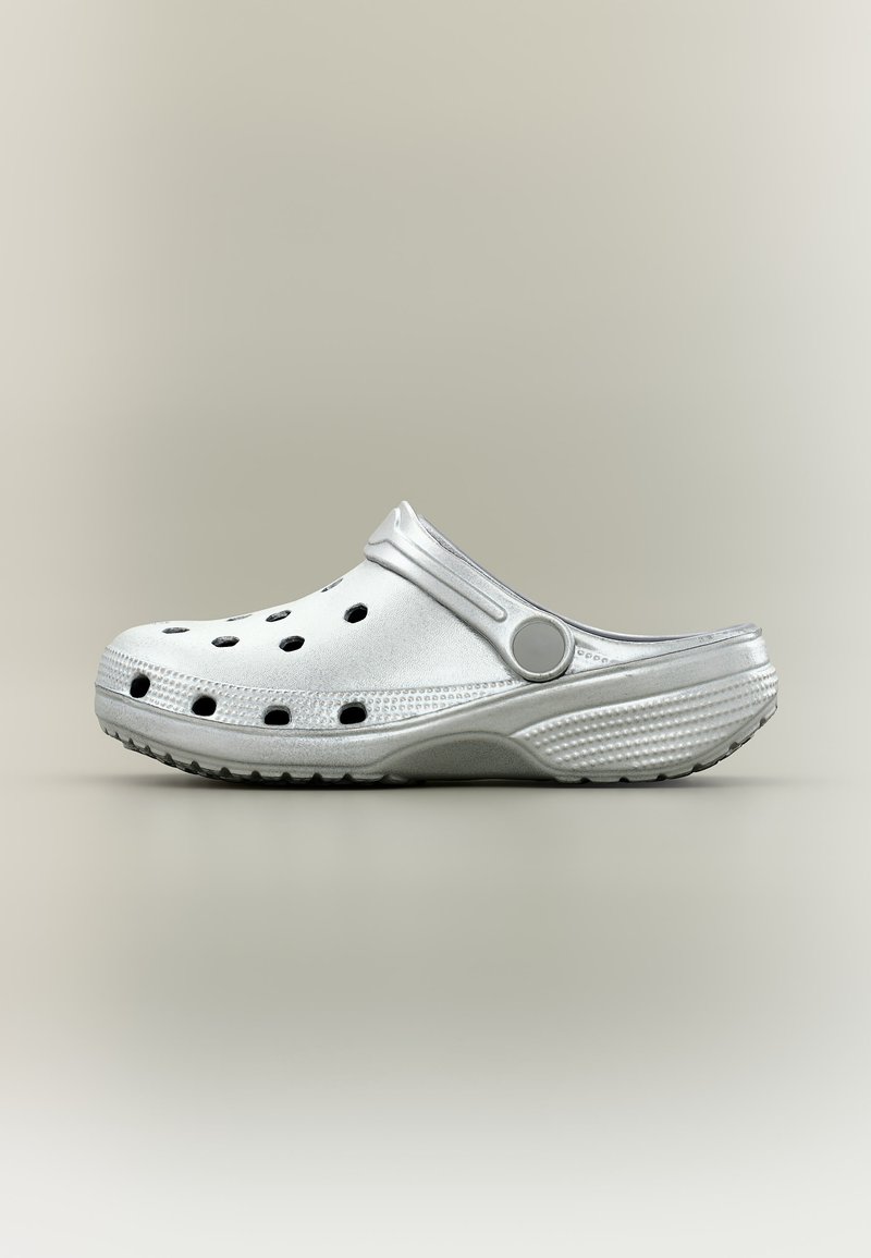 Λευκό clog τύπου slip-on με οπές αερισμού, ρυθμιζόμενο λουράκι στο τακούνι, υφή στην σόλα, εμφανίζεται πάνω σε ουδέτερο φόντο.