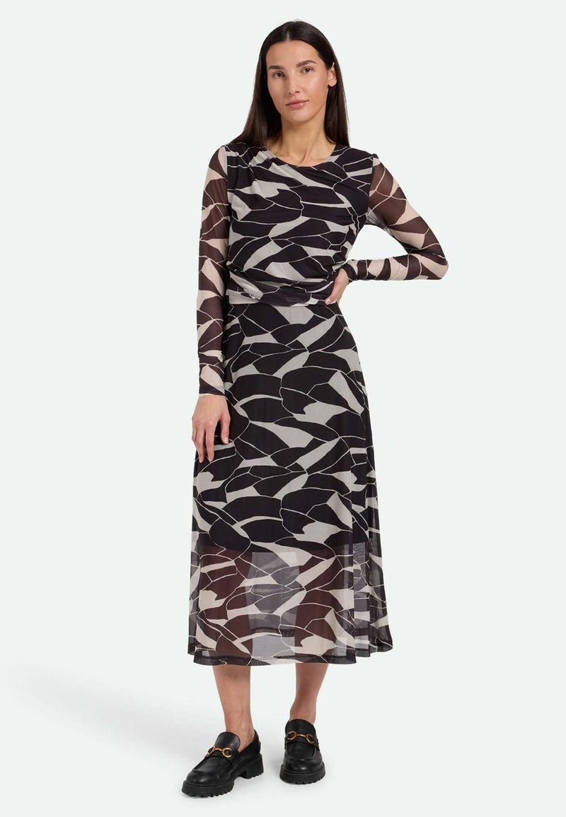Langärmliges Kleid aus transparentem schwarzem Stoff mit geometrischen beigen und grauen Mustern. Verfügt über eine geraffte Taille und eine fließende Silhouette.