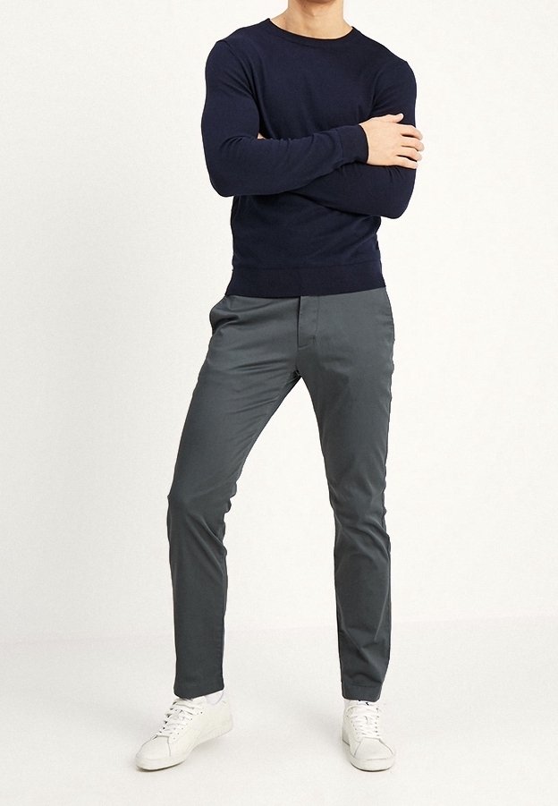 Marinblå stickad tröja i kombination med grå slim-fit byxor och vita sneakers. Outfiten har rund halsringning och en mjuk textur.