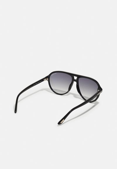 Ochelari de soare negri cu un cadru din plastic elegant și lentile gri cu nuanță gradient. Include tempii curbati și accente aurii subtile pe balamale.