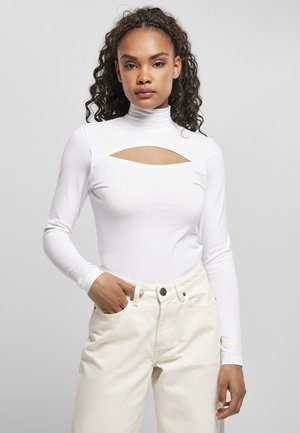 Body alb cu mâneci lungi, cu guler înalt și o decupare pătrată sub decolteu, asortat cu pantaloni de culoare deschisă, cu talie înaltă.