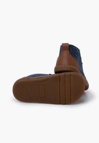 Stivaletti alla caviglia blu in suede con dettagli in pelle marrone e suola in gomma testurizzata, con un logo di scimmia sul lato.
