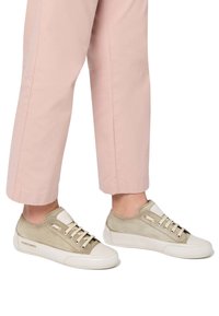 Hellbeige Sneaker mit Wildleder- und Lederdetails, runder Zehenpartie, weißer Gummisohle und beige Schnürsenkeln. Begleitet von hellrosa Hosen.