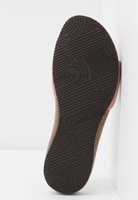 Sula av en rosa sandal med svart texturerad gummibotten och kork-mellansula, märkt "Scholl," uppställd mot vita ytor.