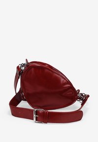 Bolso de cuero rojo con una forma de corazón única, con un acabado brillante, correa ajustable y acentos de hardware en plata.