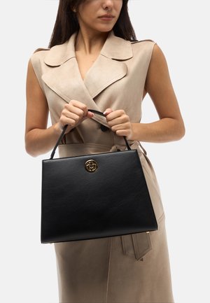 Borsa a tracolla in pelle nera con una forma strutturata, caratterizzata da un accento del logo dorato e un manico per il trasporto. Ambientata su uno sfondo neutro.