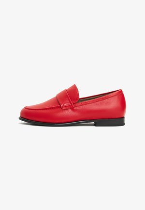Mocassino in pelle rossa con punta tondeggiante, cuciture superiori e una fascia decorativa sul davanti. Suola piatta nera, texture liscia.