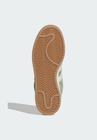 Súťažná podrážka v svetlohnedej gumenej farbe so zvlneným vzorom; zelený zamok na vrchu a biele bočné pruhy.