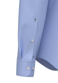 Manica di una camicia azzurra chiara con un design aderente, texture liscia, chiusura con doppio bottone e un piccolo ricamo a forma di rosa.