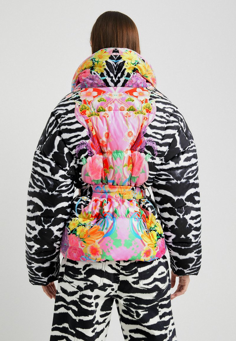 Puchowa kurtka w czarno-białe paski zebry, z różowymi kwiatowymi akcentami, wysokim kołnierzem i kolorowym wzorem na plecach z intensywnymi motywami kwiatowymi.