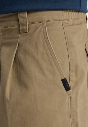 Khaki chino's met een zachte, duurzame stof en een gestructureerde afwerking, schuine zijzakken en een zwart-geel label op de tailleband.