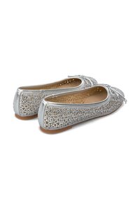 Ballerine argentate con superficie glitterata texturizzata, caratterizzate da un accento a fiocco e un design perforato. Suola piatta con interno marrone chiaro.