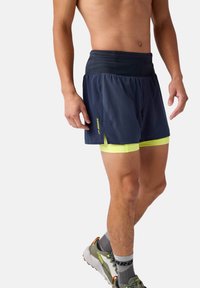 Herrlöparshorts i mörkblått, tillverkade av lätt material. Har neongula detaljer och innerfoder, samt ett flexibelt midjeband.