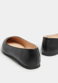 Mustat nahka-mokkasiinit pyöreällä varvalla ja sileällä pinnalla. Pehmeät beige-pohjalliset ja tyylikäs matala korko täydentävät minimalistista muotoilua.