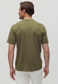 Olivengrön bomulls T-shirt med rund hals och korta ärmar, med en mjuk textur och en avslappnad passform. Bakvy visas.