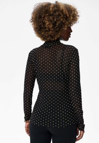 Zwarte mesh lange mouw top met een hoge hals, voorzien van een patroon van kleine gouden stippen en een getailleerde pasvorm.