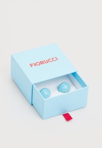 Turquoise earrings displayed in a light blue box with red "FIORUCCI" text, featuring a smooth, rounded design and a textured edge.