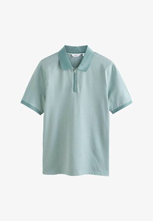 Polo de manga corta, color verde azulado claro, con tejido texturizado, cuello con cremallera y ribete en contraste en el cuello y los puños, mostrado sobre fondo blanco.