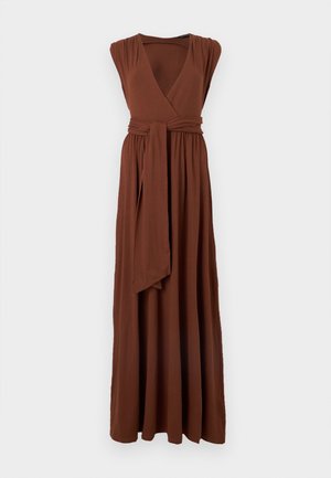 Καφέ μακρύ φόρεμα χωρίς μανίκια με V-λαιμόκοψη, σούρα στη μέση και δεμένη μακριά υφασμάτινη ζώνη μπροστά, παρουσιάζεται σε απλό ανοιχτό φόντο.