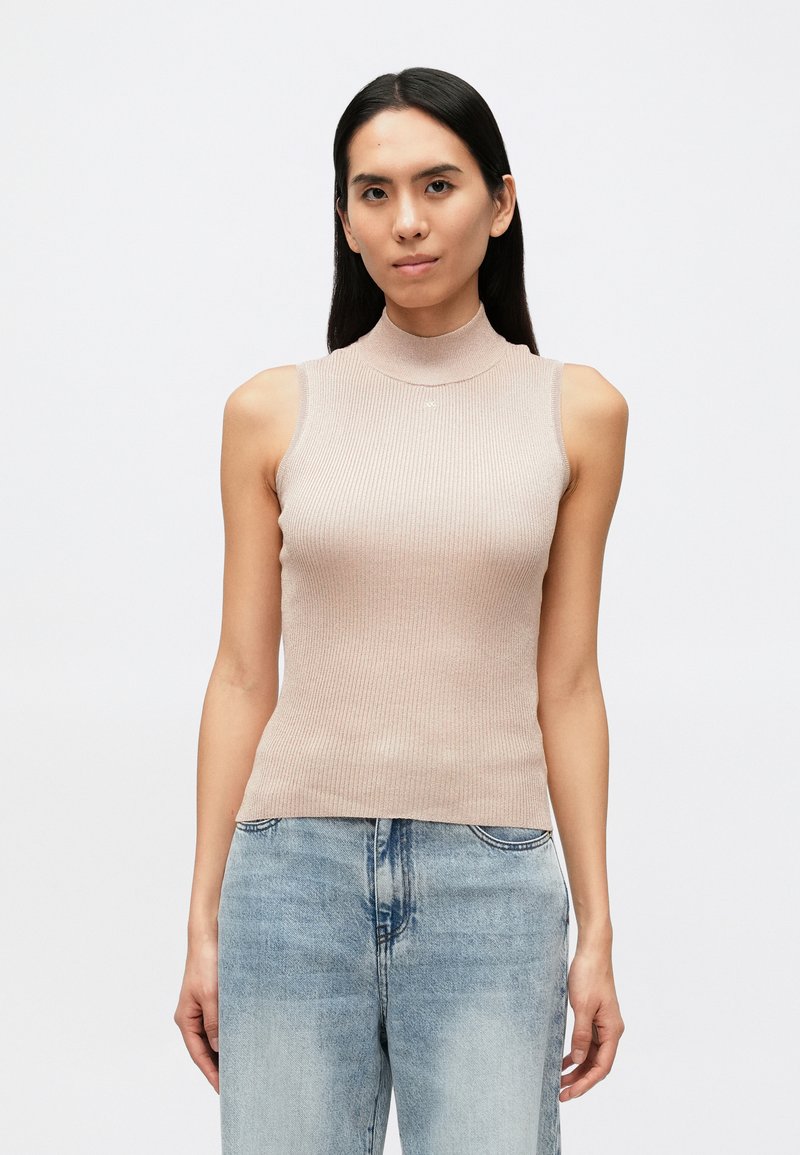 Bēša rūtainu piegriezumu bezroku topiņš ar augstu apkakli un piegulošu dizainu, izgatavots no viegla materiāla. Valdīta kopā ar gaiši zila džinsa biksēm.