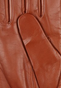 Guanti in pelle marrone caratterizzati da una texture liscia, design aderente, tre cuciture sul retro e un taglio dritto al polsino.