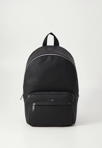 Juoda odinė kuprinė su apvaliu viršumi, priekine kišene su užtrauktuku ir dviem petnešomis. Turi lygią tekstūrą ir minimalistinius metalinius elementus.