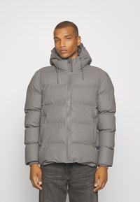 Giubbotto imbottito grigio con cappuccio, dotato di zip frontale e polsini elasticizzati, caratterizzato da una texture trapuntata e design voluminoso.