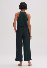 Mörkgrön stickad linne topp i kombination med lösa, svarta linnbyxor som har resårmidja och sidofickor.