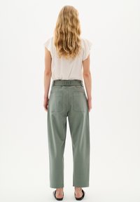 Pantaloni olive green a vita alta con una vestibilità rilassata, dotati di due tasche posteriori e un tessuto liscio, leggermente testurizzato.