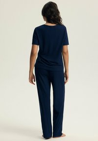 Granatowy zestaw piżamowy z prążkowanej tkaniny, składający się z bluzki z krótkim rękawem i długich spodni o luźnym kroju. Miękka struktura i prosty design.