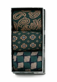 Drei gemusterte Stoffrollen in einer Box. Oben: grün mit beigen Wirbeln. In der Mitte: grün mit floralen Motiven und blauen Akzenten. Unten: karierter Muster in grün und beige.