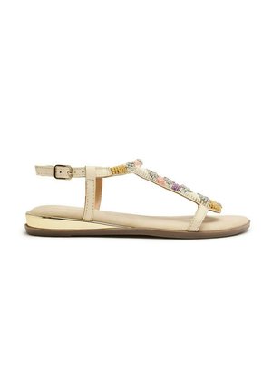 Sandali piatti beige con una cintura decorativa di perline; presentano un sottile cinturino alla caviglia e un accento dorato sulla suola per un tocco in più.
