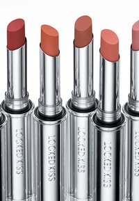 Sex läppstift med silvermetalliska höljen som visar nyanser från djup röd till mjuk nude, med släta, matta ytor.