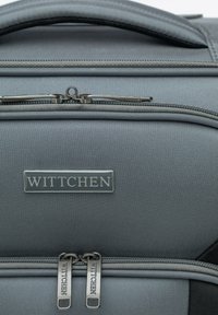 Sac à dos en tissu gris avec une surface texturée, double zippers avec la marque "WITTCHEN" et une poignée robuste en haut.