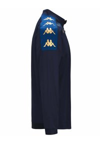 Polo de manga larga azul marino con puños acanalados, que presenta un panel azul en el hombro adornado con cinco logotipos dorados.