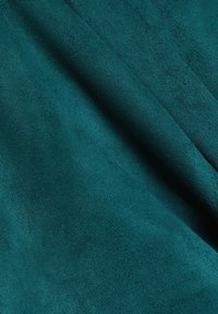 Tissu doux vert sarcelle foncé avec des plis subtils et une texture lisse et veloutée montré de près.
