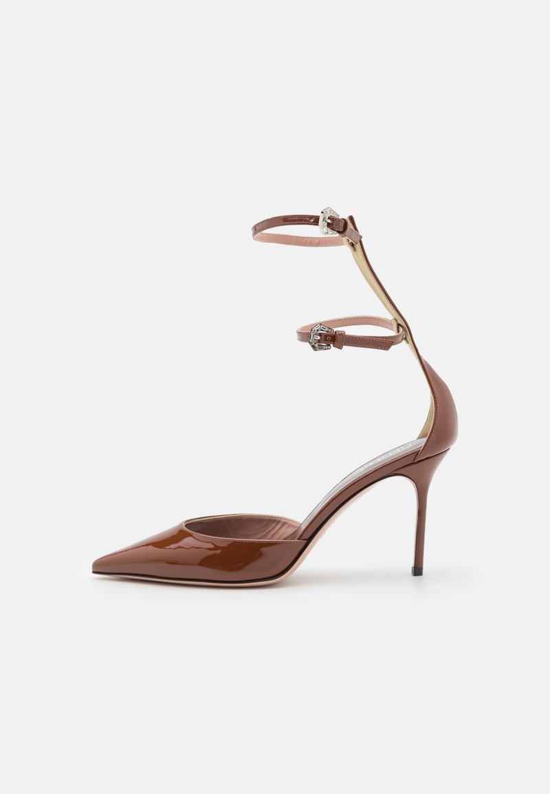 Zapato de tacón alto de piel charol marrón con punta afilada y laterales recortados; cuenta con dos correas en el tobillo ajustables y un tacón de aguja.